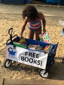 Girl in striped swimsuit selecting books from the Cleveland Kids' Book Bank wagon