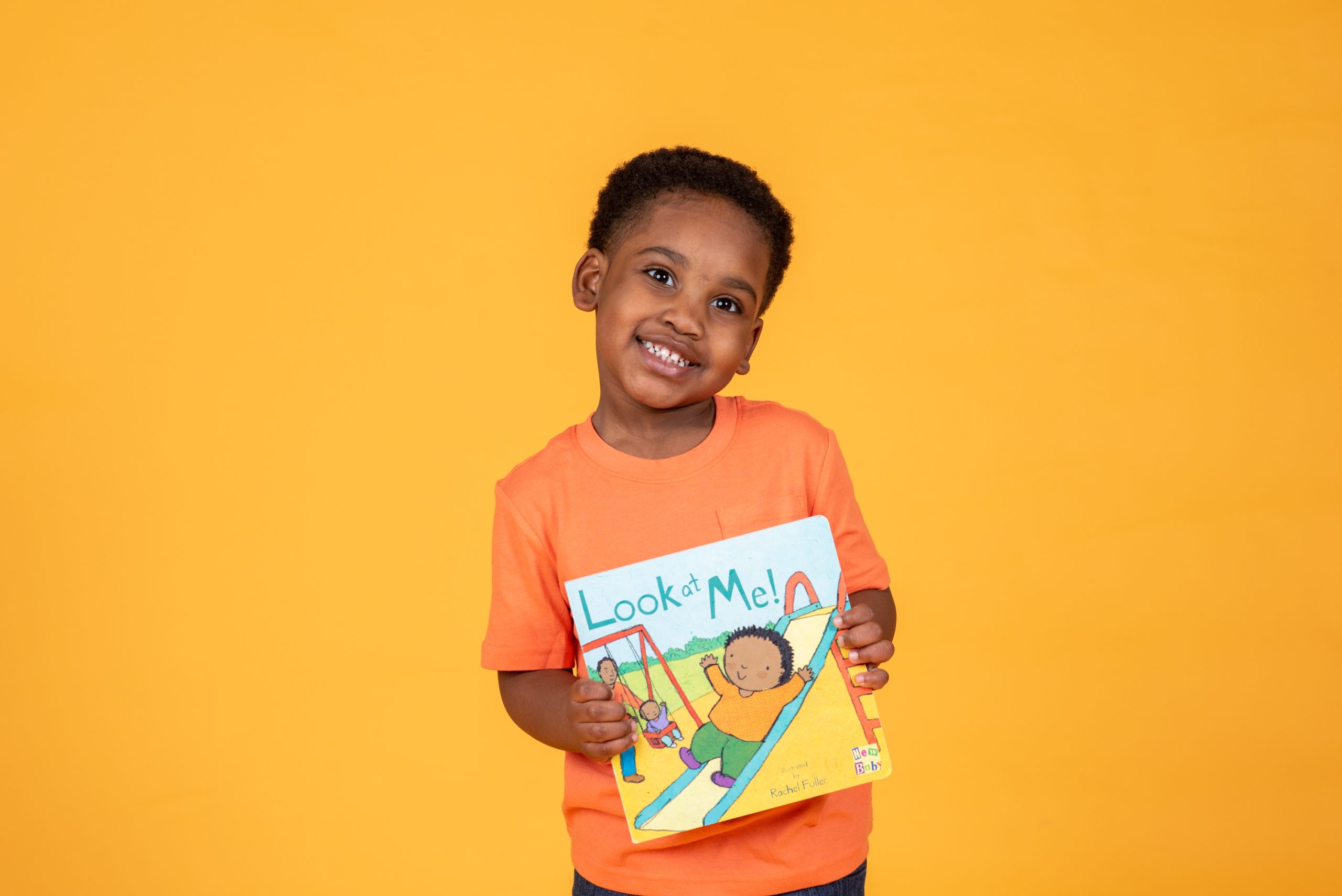 CoCreative Kids Book Bank boy against yellow background holding book