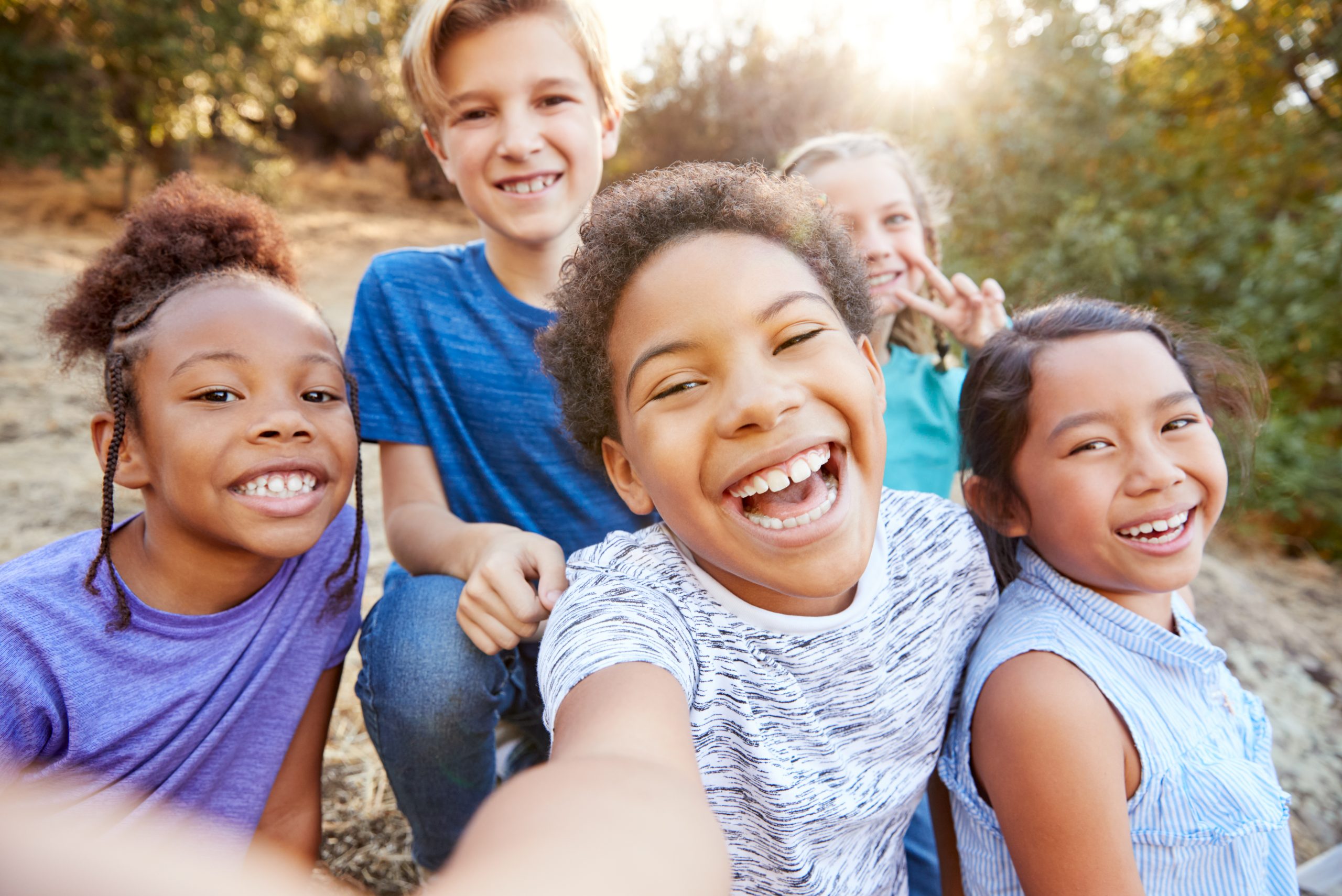 group of five kids laughing and smiling at the camera