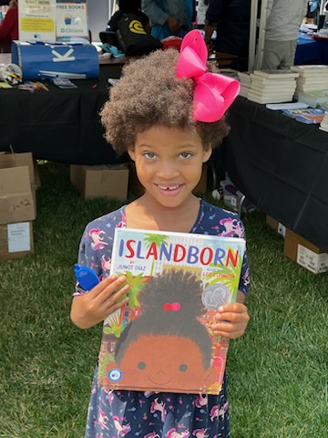 IslandBorn girl holding the book Island Born at Juneteenth event