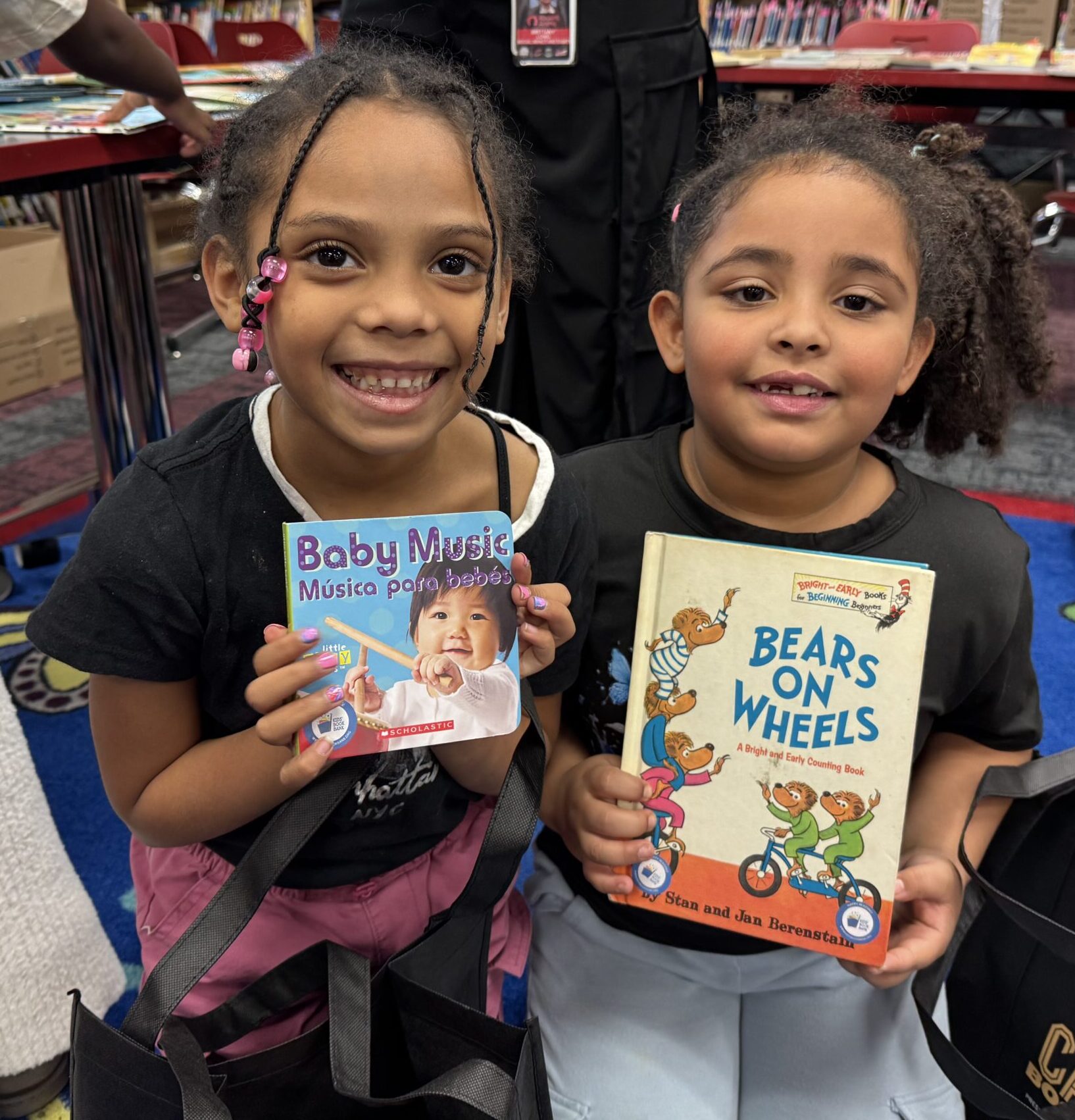 two girls kneel each holding a book