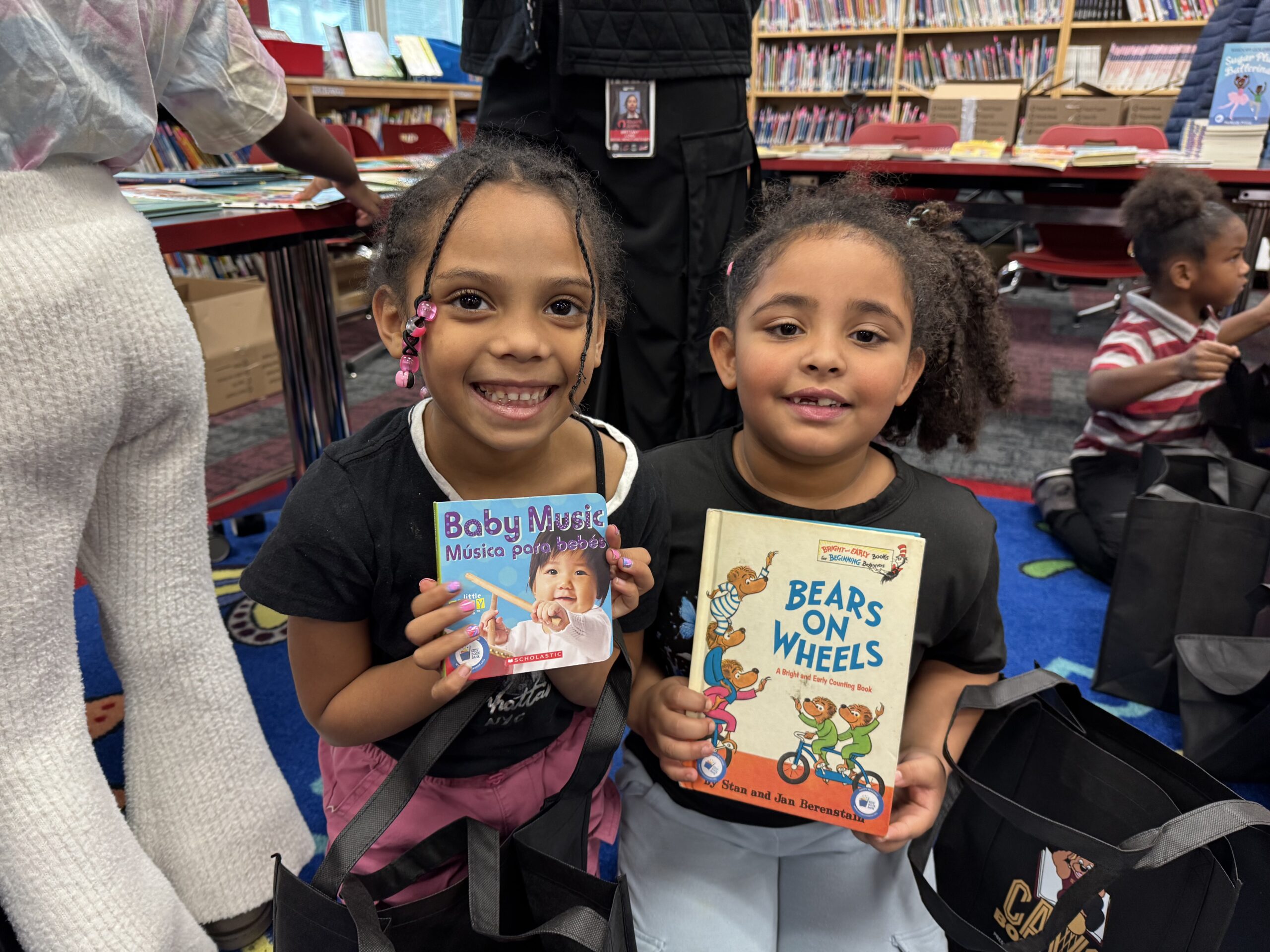 two girls kneel each holding a book