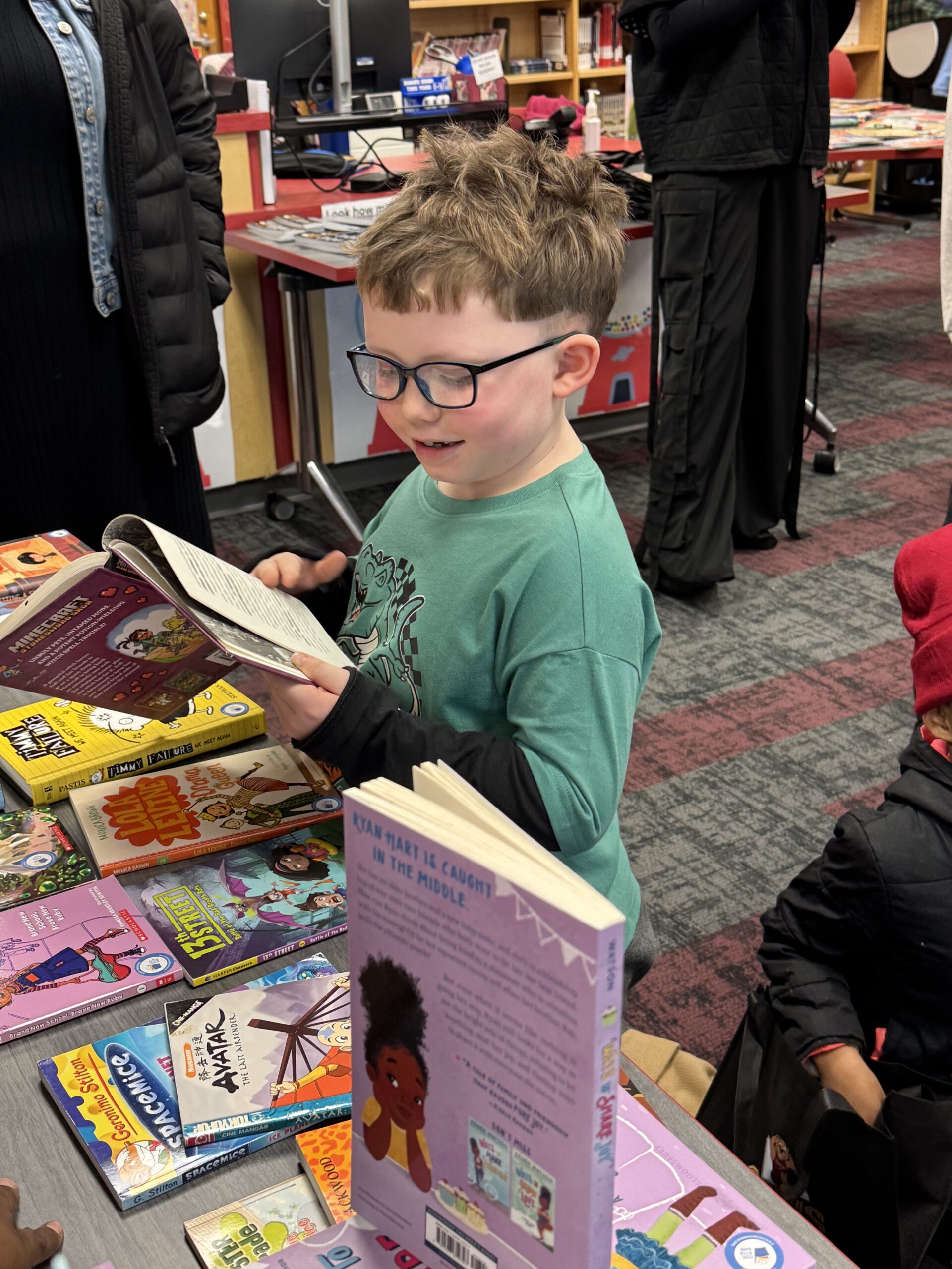 boy with glasses standing and reading a book
