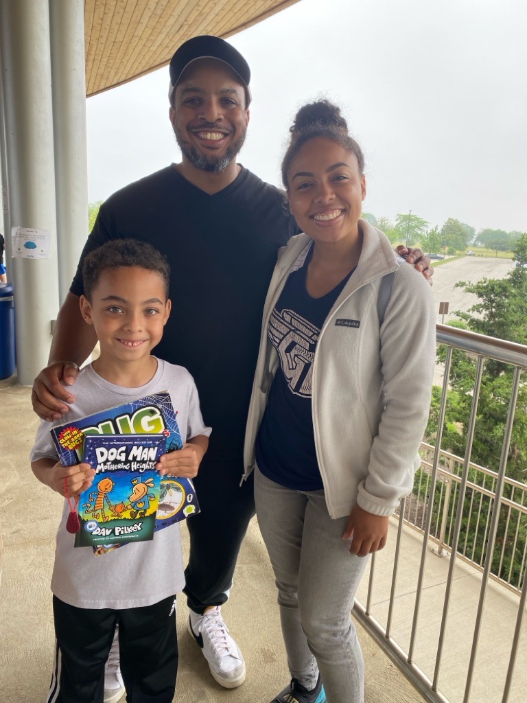 man woman and boy standing holding books