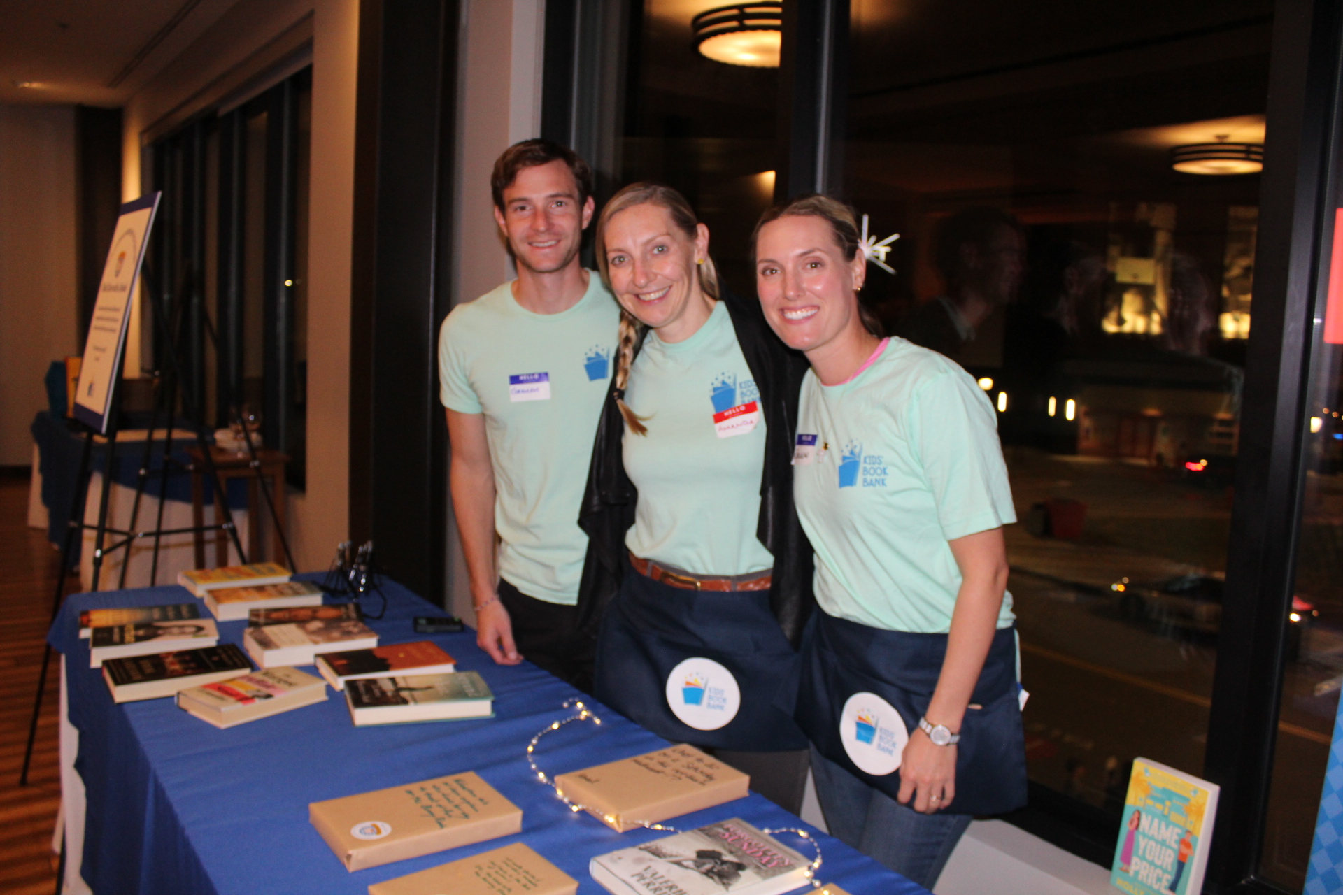 three people stand behind a table of wrapped books